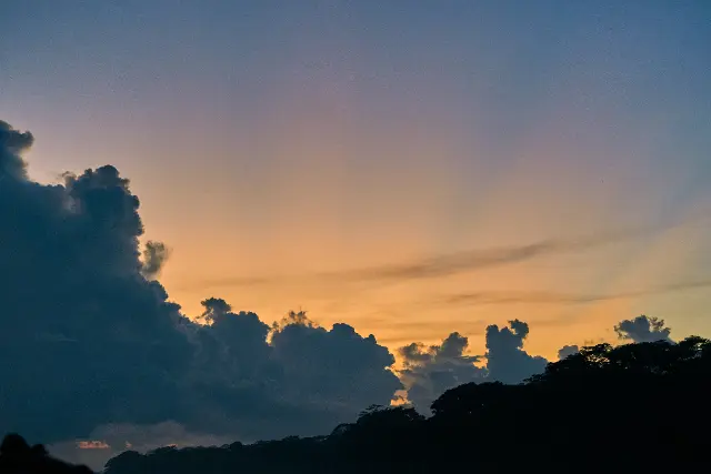 Fluffy dark clouds silhouette against a glowing sunset sky.